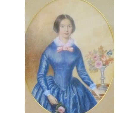 A Victorian watercolour portrait of a young woman in a blue dress beside a vase of flowers, unsigned, 21cm x 16.5cm, housed i