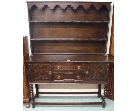 A 20th century oak Jacobean style kitchen dresser with two shelf open plate rack over two central drawers flanked by cabinet 