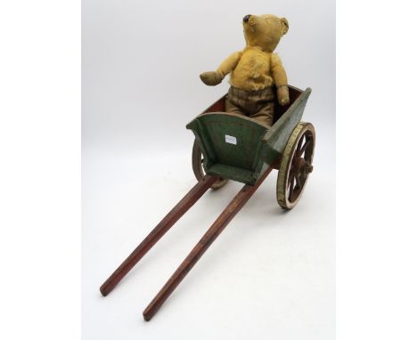 A threadbare vintage teddy, riding in a miniature polychrome-painted pine cart, measuring approx. 54cm in length Condition Re