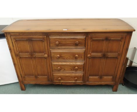 A 20th century elm and beech Ercol golden dawn sideboard with four central drawers flanked by panel doors, 90cm high x 146cm 