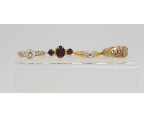 A 9ct gold ruby and diamond star set ring, size approx L, a three stone garnet ring, size K1/2, and two clear gem set rings, 