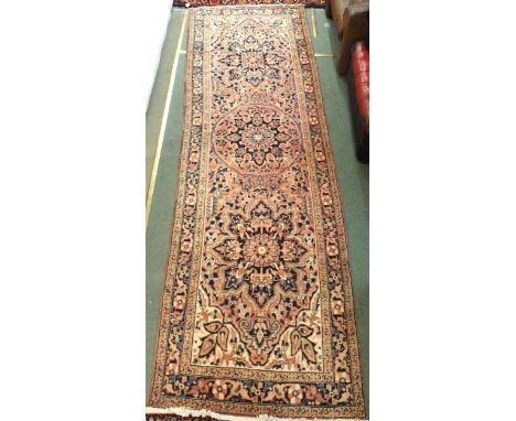 A pink ground Heriz runner with three multicolour medallions, beige spandrels and multicoloured floral borders, 352cm long x 