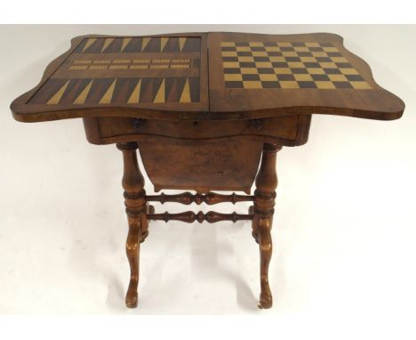 A Victorian walnut and satinwood inlaid fold over games table with serpentine fold over top concealing inlaid chess, backgamm