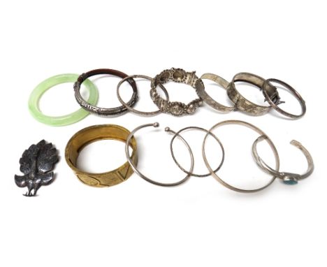 A Victorian gilt metal oval hinged bangle decorated in the Aesthetic Movement taste, a green paste circular bangle, ten furth