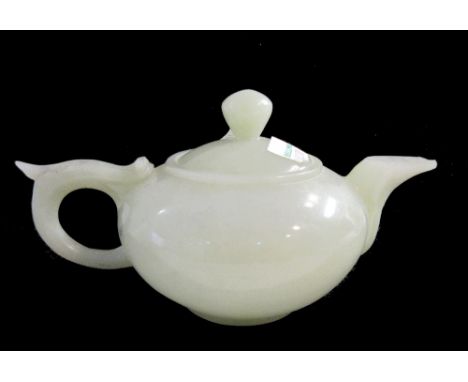 A Chinese reconstituted jade teapot and cover, 20th century, of compressed globular form, the top of the handle carved with a