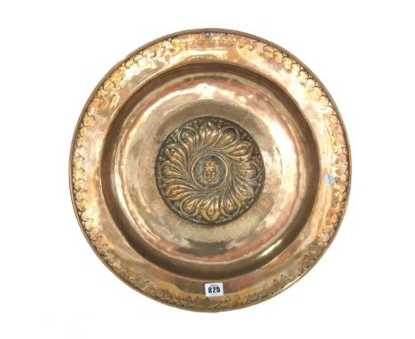 A German brass alms dish, 16th century, raised boss decorated with a mask within a foliate border, 49cm diameter. 