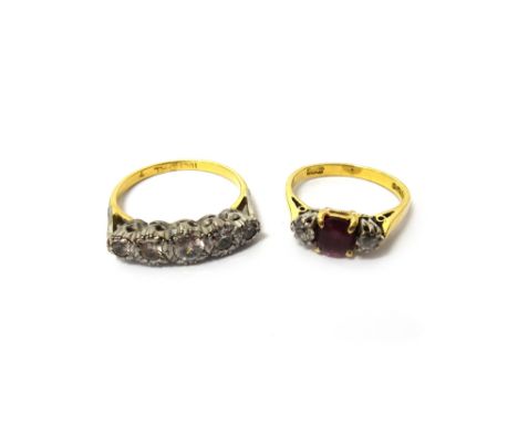 An 18ct gold, ruby and diamond set three stone ring, claw set with an oval cut ruby at the centre between two cushion shaped 