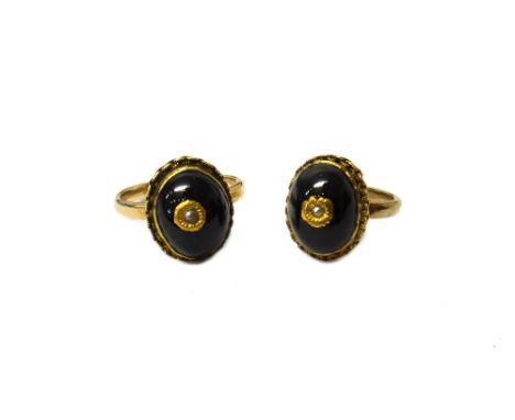 Two gold and carbuncle garnet set rings, each oval carbuncle garnet mounted with a seed pearl at the centre within a chain wo