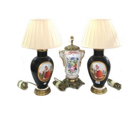 A pair of Continental porcelain table lamps, each decorated with a female figure against a gilt and black ground with pleated