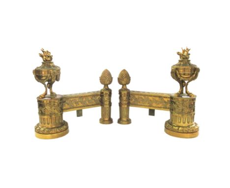 A pair of French Louis XVI style ormolu chenets, early 20th century, each with flaming urn finial and opposing 'pineapple' fi