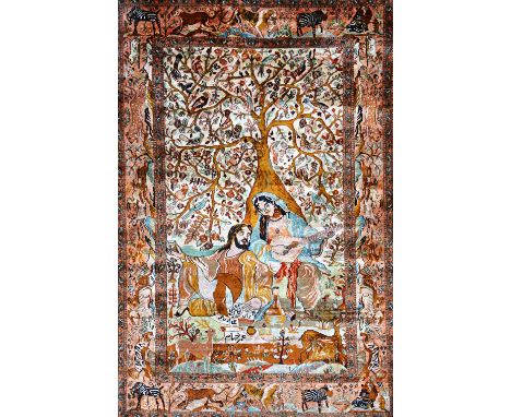 A fine Indian silk pictorial rug, depicting a couple resting under a flowering tree, the woman playing an instrument, with a 