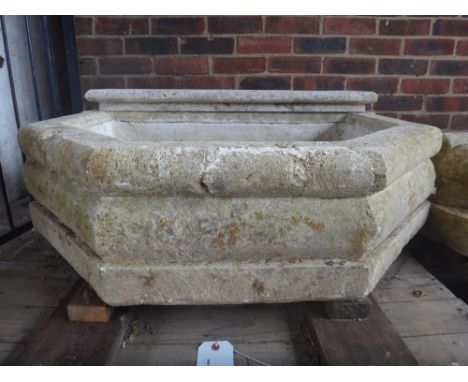 A carved limestone wall fountain, with face mask spout and canted rectangular reservoir, 105cm wide x 85cm deep.
