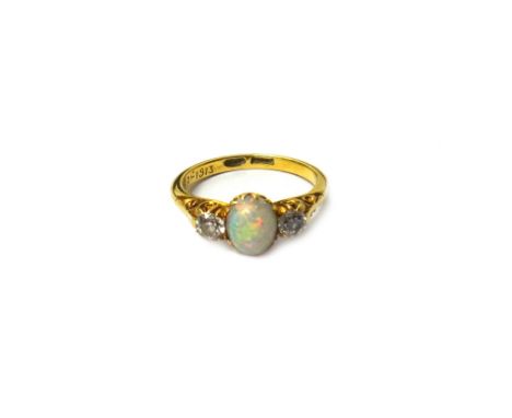 A gold, opal and diamond set three stone ring, claw set with the oval opal at the centre between two cushion shaped diamonds,