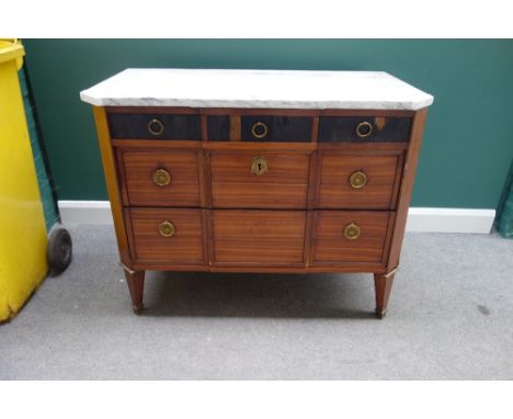L. Gilbert; a late 18th century French commode, the shaped marble top over three short ebony veneered drawers and two further