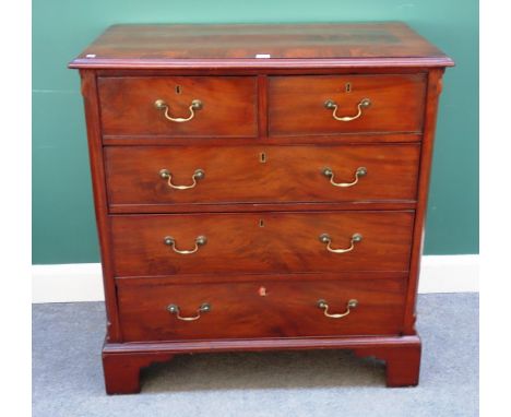 A George III crossbanded mahogany chest of two short and three long graduated drawers, flanked by canted corners, on bracket 