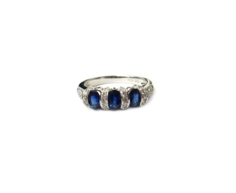 A white gold, sapphire and diamond ring, mounted with three oval cut sapphires, between four rows of circular cut diamonds, b