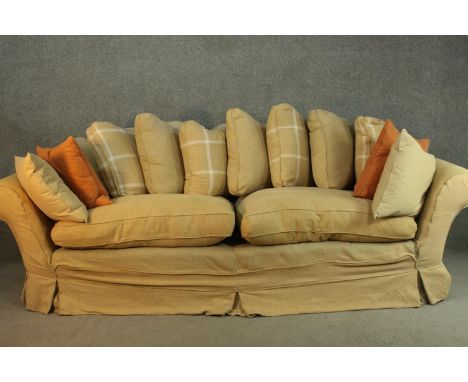 A contemporary three seater sofa, upholstered in ochre fabric, with scrolling arms and a selection of loose cushions. H.90 W.