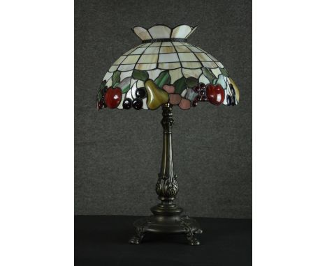 A Tiffany style table lamp, with a stained glass shade depicting fruit, the bronzed brass base with a slender baluster stem c