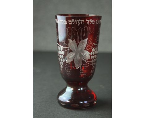 A 19th century ruby cut to clear Bohemian glass Kiddush cup, with engraved vine and Jewish character design. H.15 Dia.7cm. 