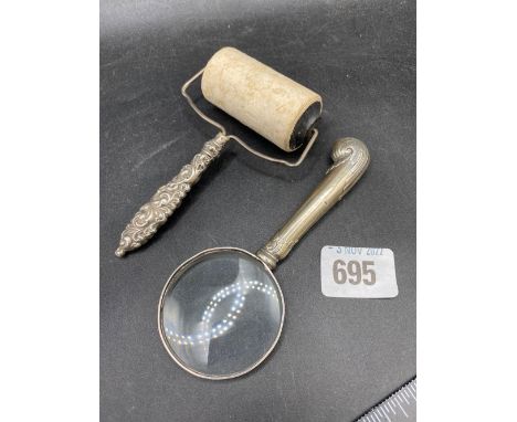 A silver handled stamp roller an a magnifying glass with silver handle