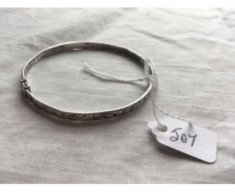 A slim silver bangle with floral design BY CHARLES HORNER