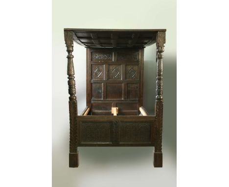 A 17TH CENTURY OAK TESTER BED the tester panelled, the head board with foliate carved panels above lozenge carved panels, the