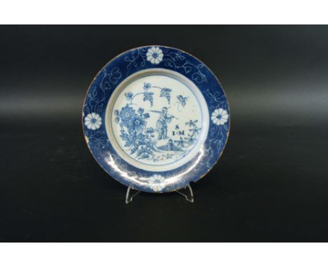 A BLUE AND WHITE DELFTWARE MONOGRAMED PLATE painted with a chinoiserie garden scene, initialed S I . M, the powder blue borde
