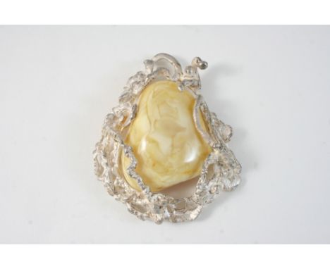 AN AMBER AND SILVER PENDANT set with a section of amber in silver openwork mount, 10 x 8cm.