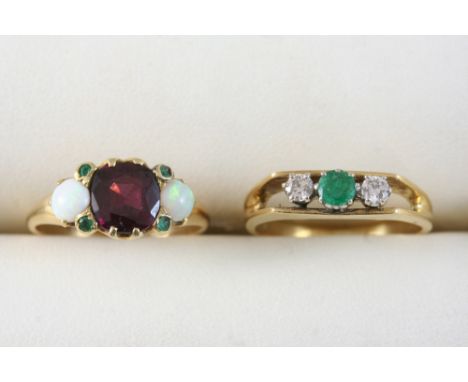 A GARNET, OPAL AND DIAMOND RING set with an oval shaped garnet, two cabochon opals and four small emeralds, in gold, size M, 