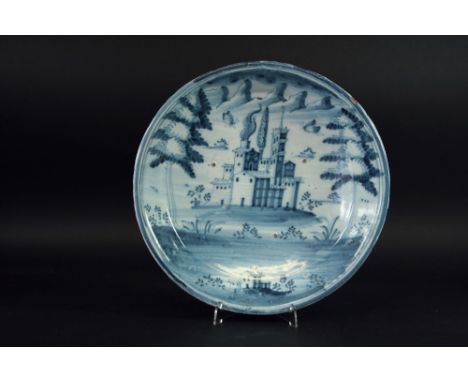 A DELFTWARE BLUE AND WHITE SHALLOW BOWL painted with a church before a mountainous background, 12 1/2 ins. (32cms.) dia.