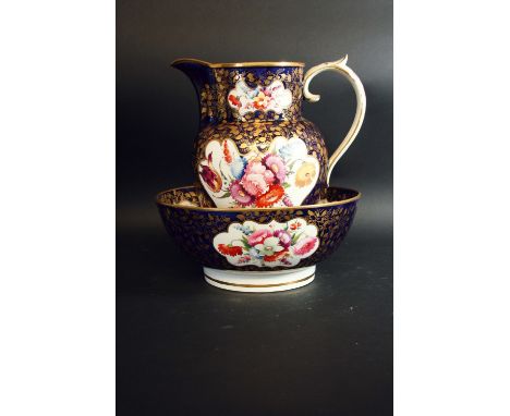 A JUG AND BASIN boldly painted with cartouches of floral sprays, reserved on a solid dark blue ground enriched with gilt foli