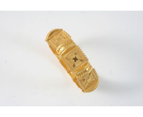 AN ORNATE GOLD BANGLE with engraved and embossed decoration, 47 grams.