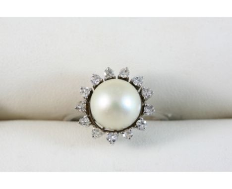 A CULTURED PEARL AND DIAMOND RING set with a cultured pearl within a surround of small diamonds, in gold. Size Q.