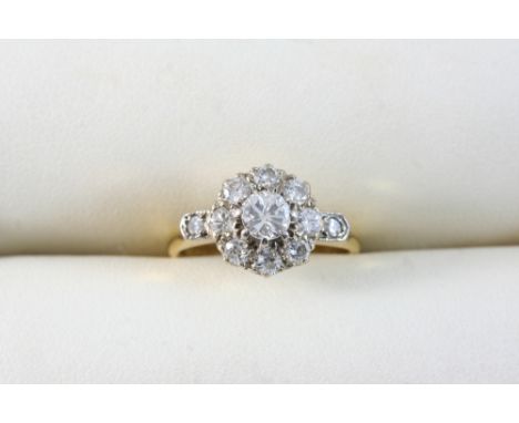 A DIAMOND CLUSTER RING set with a circular-cut diamond within a surround of eight smaller circular-cut diamonds, with a small