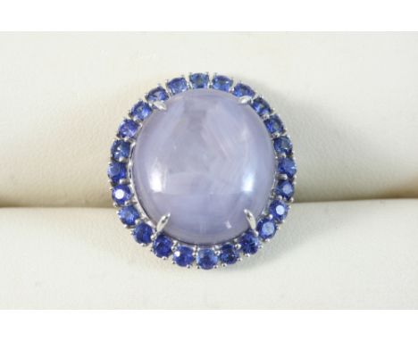 A STAR SAPPHIRE, SAPPHIRE AND DIAMOND CLUSTER RING set with an oval-shaped star sapphire within a surround of circular-cut sa