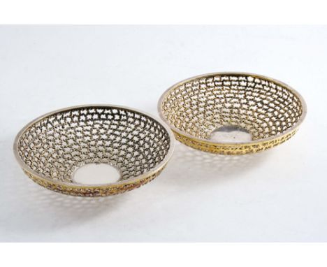 BY STUART DEVLIN: A pair of modern parcelgilt dishes of shallow circular form with pierced & textured work, London 1970;  6" 
