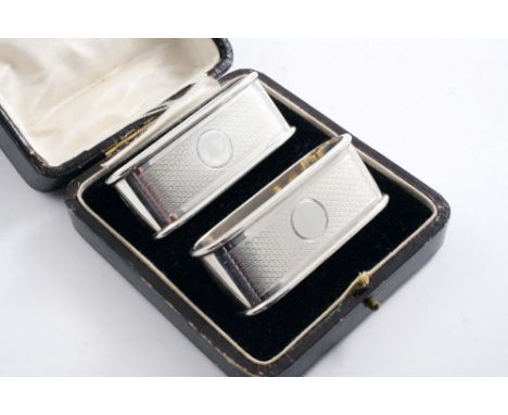 A MODERN CASED PAIR OF ENGINE-TURNED NAPKIN RINGS of rounded oblong form, maker's mark  "G.P&Co", Chester 1926;  2.9"  (7.4 c