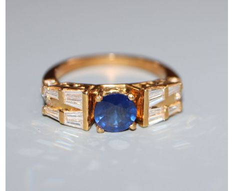 A modern 750 yellow metal, single stone sapphire dress ring, flanked with round and trapeze cut diamonds, size O.