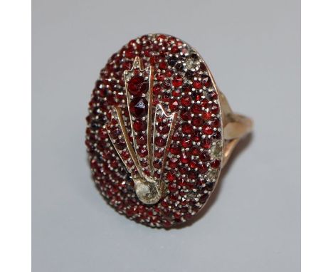 A large Victorian yellow metal and facet cut garnet encrusted oval dress ring, size R.