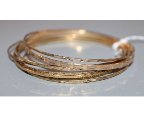 A 9ct gold narrow bangle with engine-turned decoration and seven other narrow bangles.