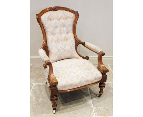 A Victorian walnut open armchair, the shaped button back extending to padded out swept arms with roundel terminals, above the