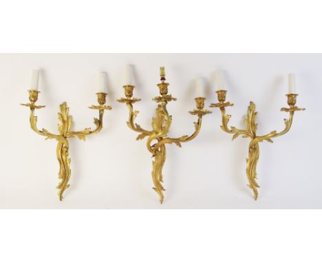 Three Rococo style wall sconces, each of foliate form, one with three branches and a pair with twin branches, each branch wit