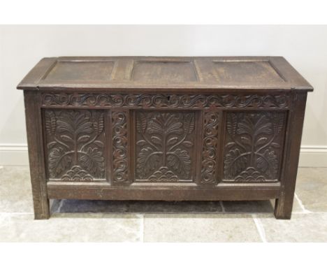 An early 18th century oak triple panel coffer, profusely carved with a scrolling repeating frieze over the three panels carve