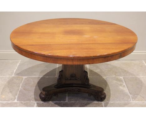 A William IV rosewood breakfast table, the circular tilt top raised on a triform pedestal applied with carved scroll ears, up