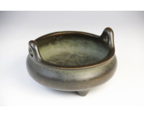 A Chinese bronze censer, of squat bulbous form with loop handles raised on three tapered feet, nine character Kaishu seal mar