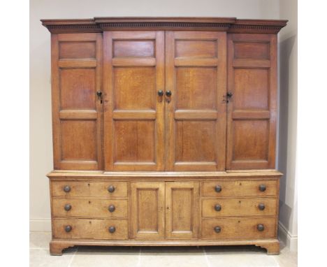 A George III honey oak breakfront housekeepers cupboard, the moulded cornice with a dentil frieze above an arrangement of fou