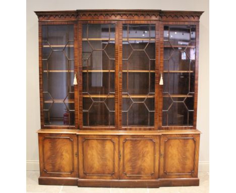 A George III style breakfront mahogany library bookcase, late 20th century, the dentil and arcaded frieze above four astragal