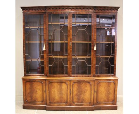 A George III style breakfront mahogany library bookcase, late 20th century, the dentil and arcaded frieze above four astragal