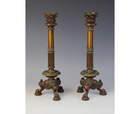A pair of patinated bronze candlesticks in the manner of William Bullock, 20th century, the tri-form bases with paw feet supp