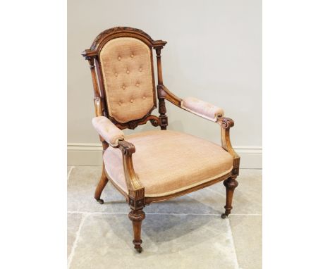 A French walnut salon chair, circa 1880, the arched button back below leaf and berry carved detail and flanked by architectur